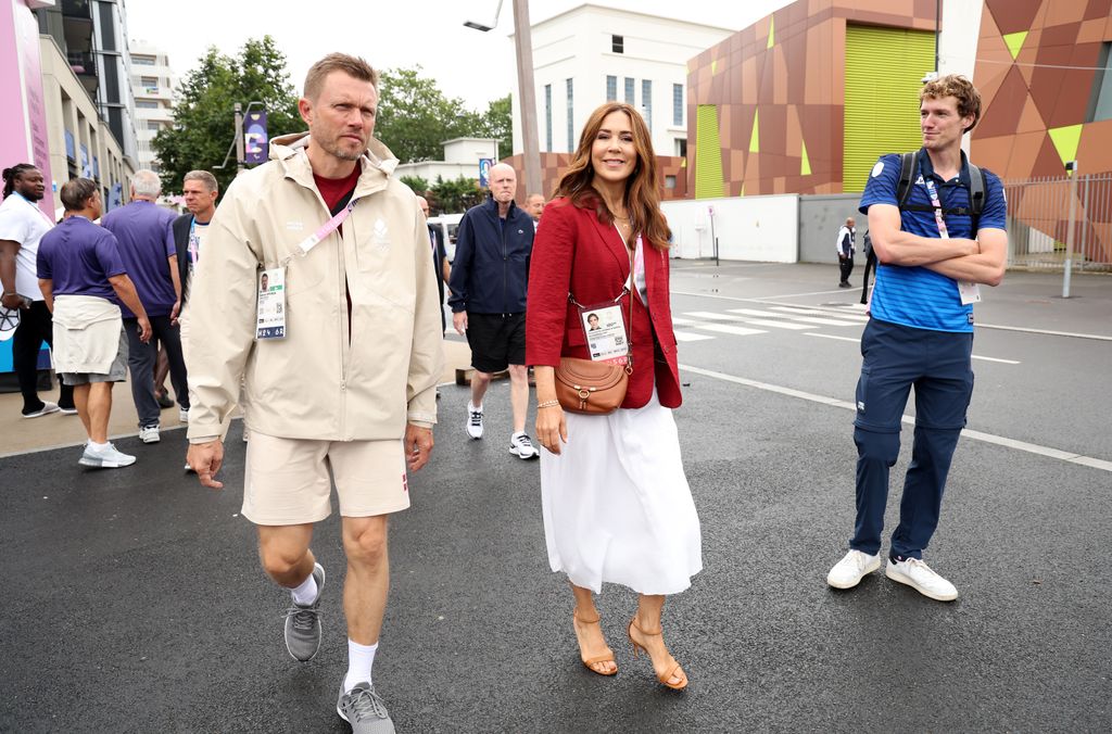 Queen Mary walking in white dress and red blazer 