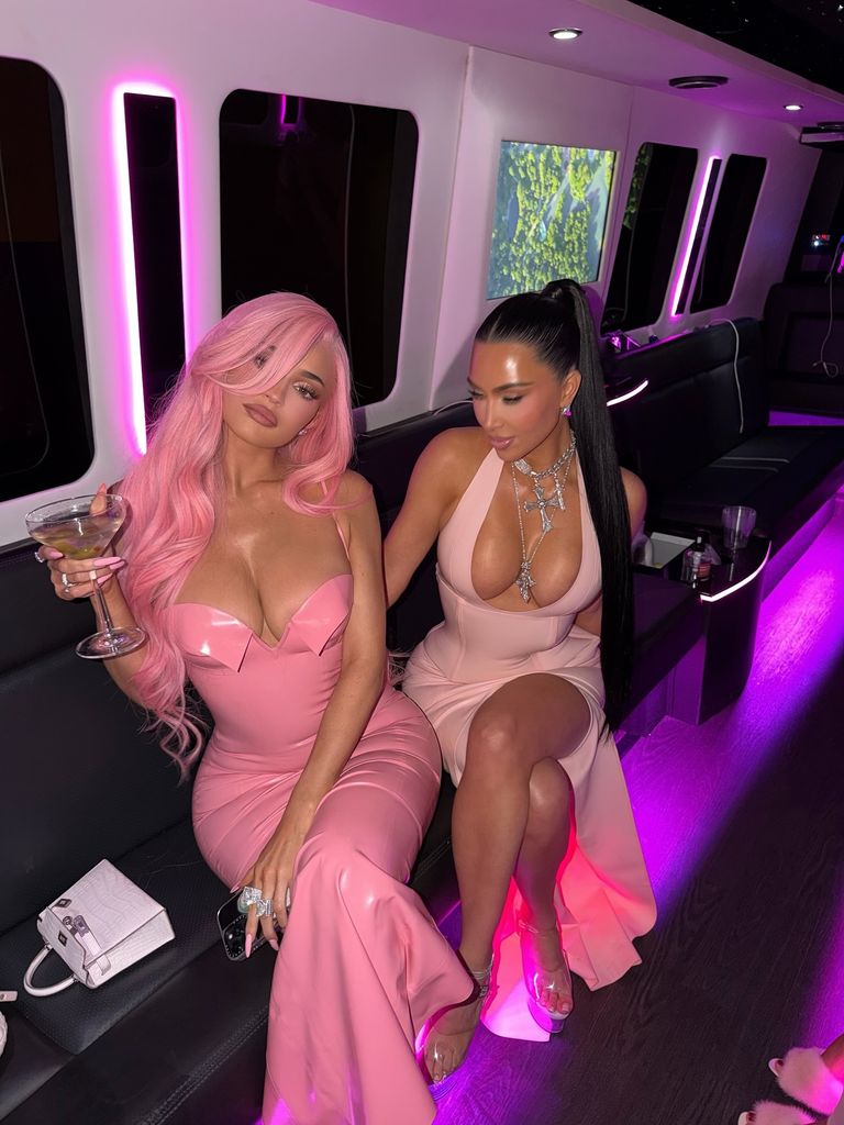 Kylie Jenner + Kim Kardashian wearing pink vinyl dresses as they pose for the camera