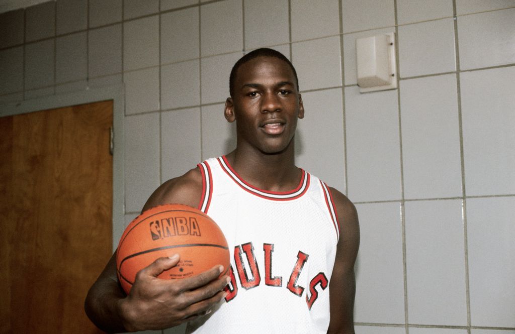 Michael Jordan, forward for the Chicago Bulls, holding a basketball in the locker room, in 1984