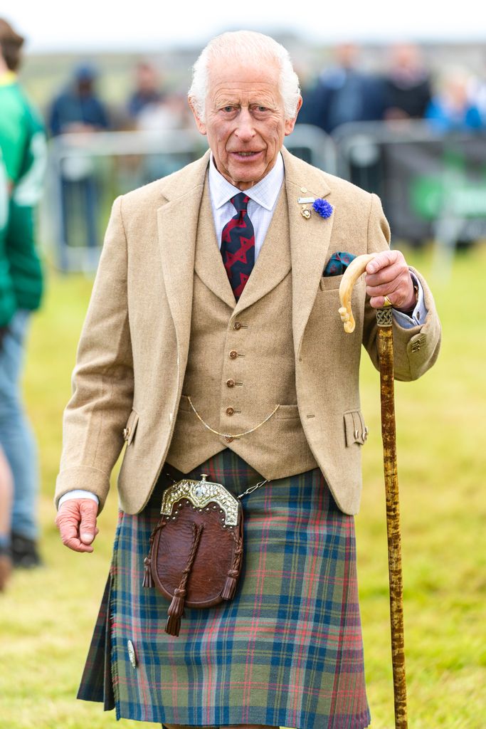 King Charles in a tan coat and kilt