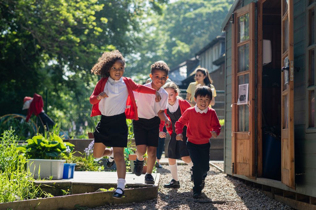 A medium close-up of a group of school children running in the school yard as they head to playtime 