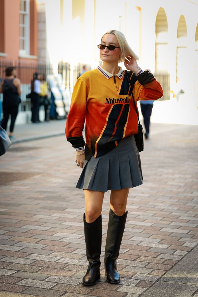 LONDON, ENGLAND - SEPTEMBER 19: A guest wearing yellow and orange top, grey mini skirt and black knee boots outside Bora Aksu during London Fashion Week on September 19, 2025 in London, England.  (Photo by Hanna Lassen/Getty Images)