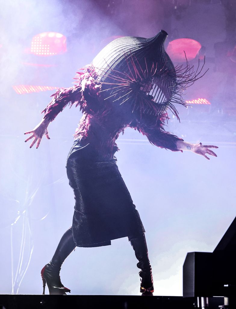 Lady Gaga se produit sur scène dans une jupe crayon en cuir, un haut perlé et un casque cage