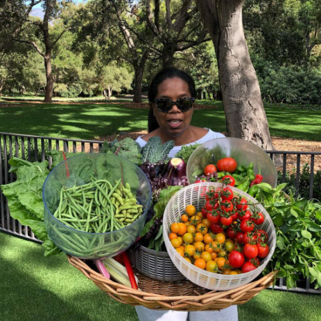 Oprah holding fresh produce from her garden with sunglasses on 