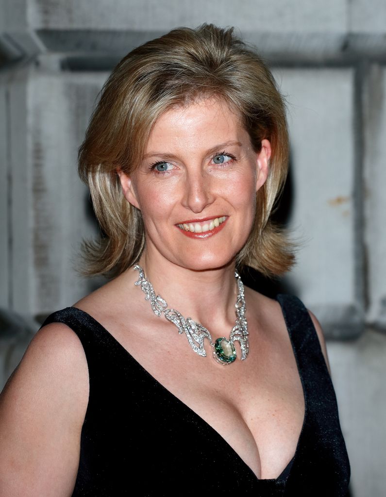 Sophie looks to left in black v neck dress