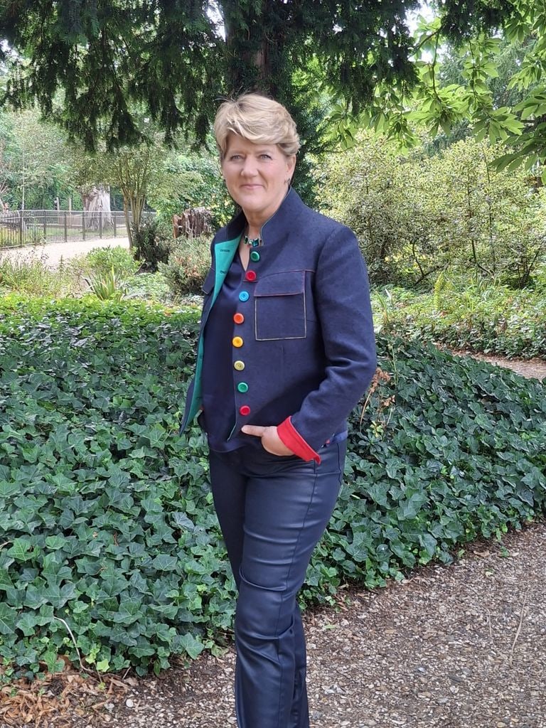 Clare Balding posing in denim jacket with bright buttons and jeans 