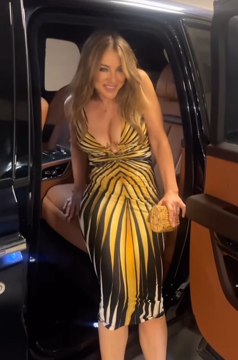 Elizabeth Hurley em um vestido com estampa animal entrando em um carro