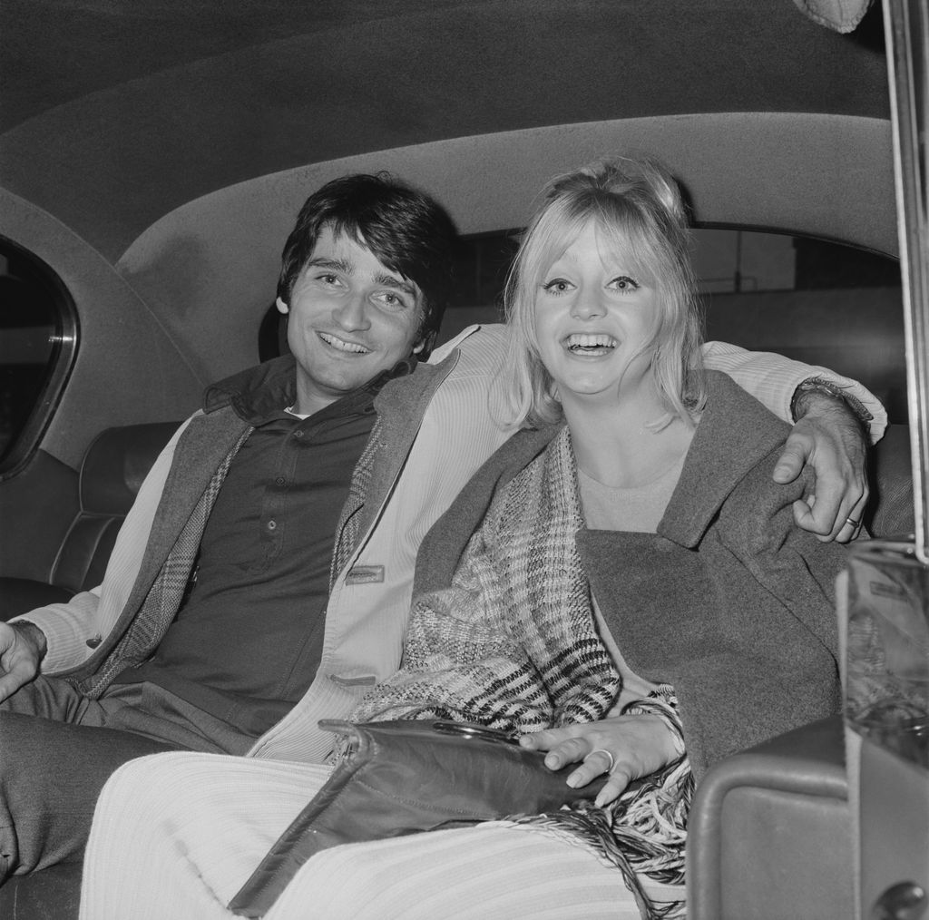 Goldie Hawn with her husband, American actor, dancer and director Gus Trikonis sitting in the back seat of a car at Heathrow Airport, London, UK, 23 March 1970