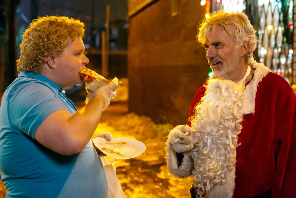 Brett eating pizza with billy bob thornton in a santa suit