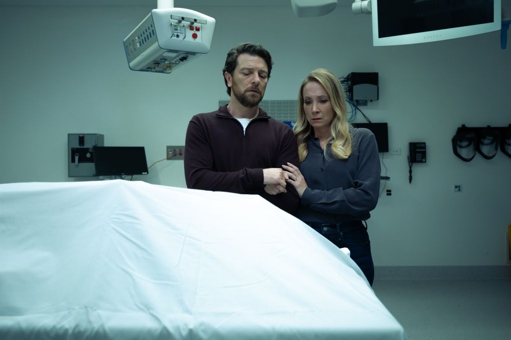 A man and woman upset while looking at body covered by white sheet