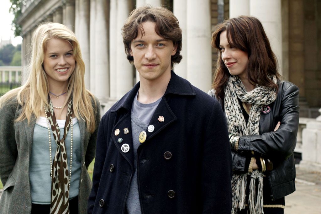 male uni student standing in front of two female uni students