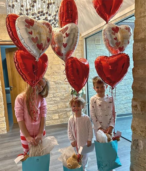 Three children with heart shaped balloons
