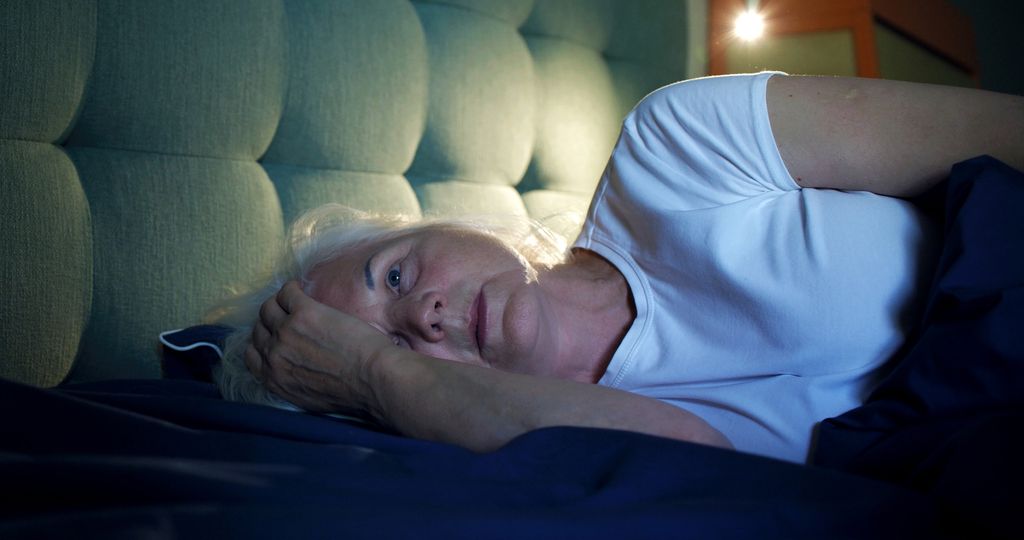 Mature, sleep-deprived woman feeling frustrated in bed.