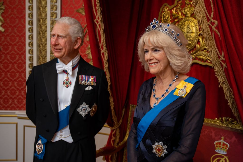 Waxwork figures of King Charles in black suit and Queen Consort Camilla in navy blue gown
