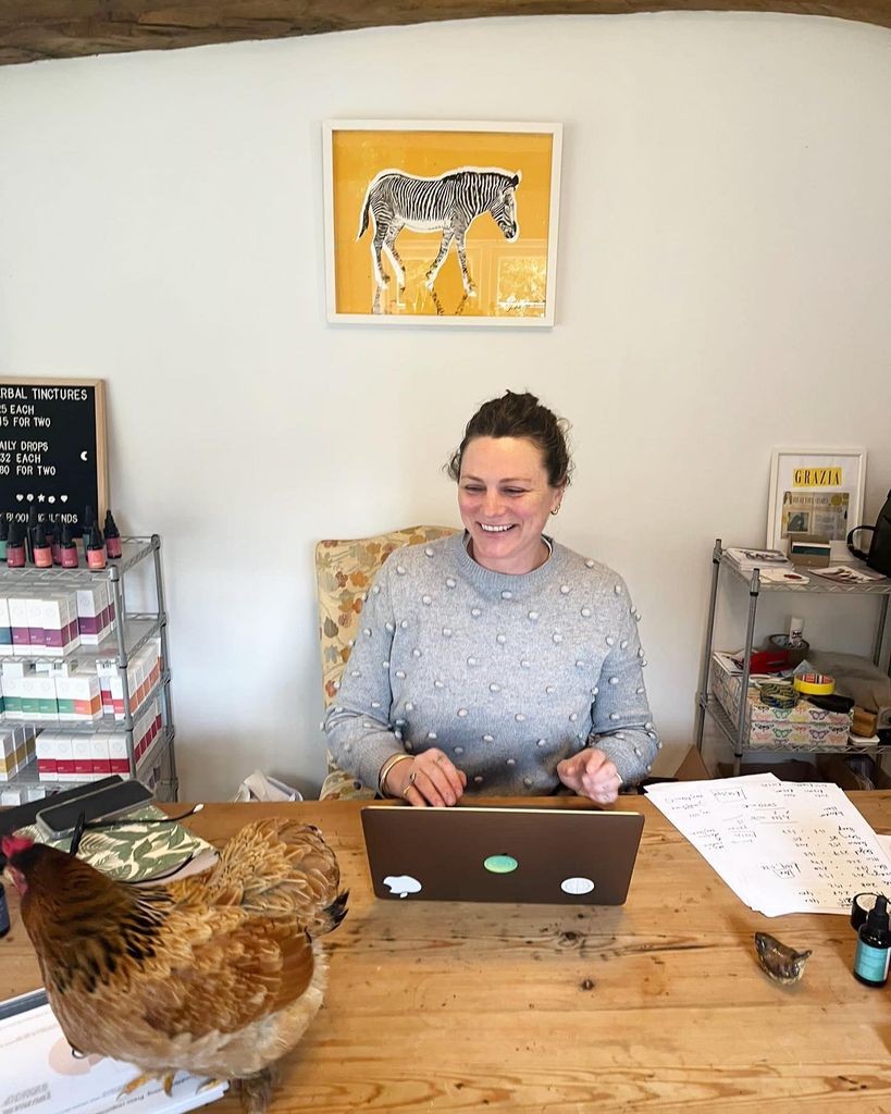 Woman sitting at her laptop at a wooden desk 