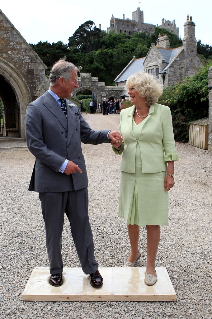 Charles and Camilla hold hands as they make imprints of their feet for a cast