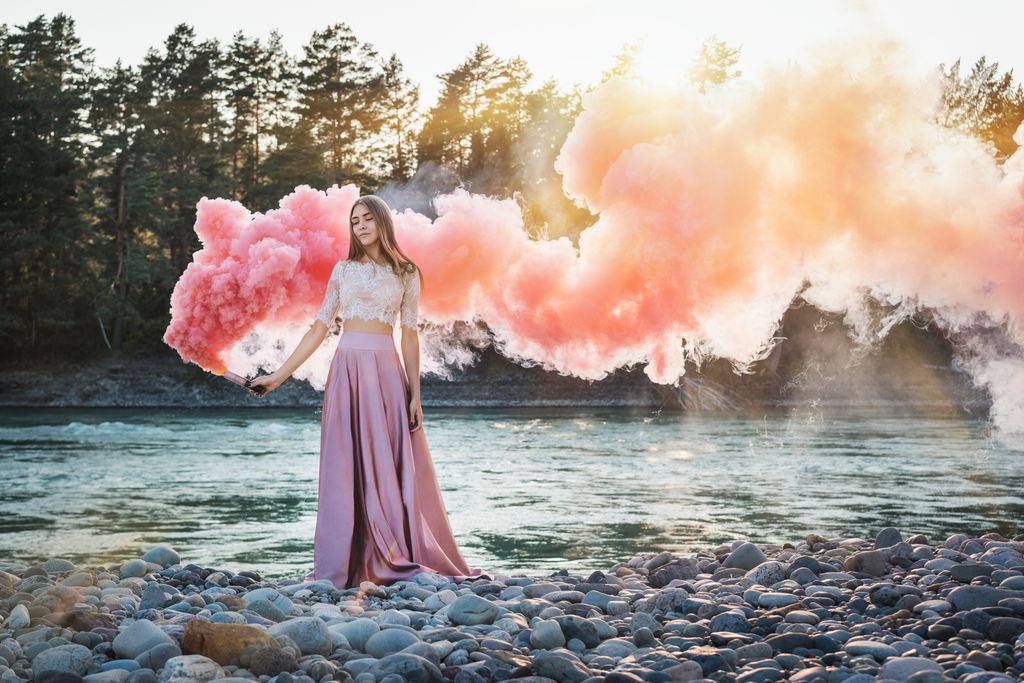 Girl in lace top and pink skirt holding pink smoke