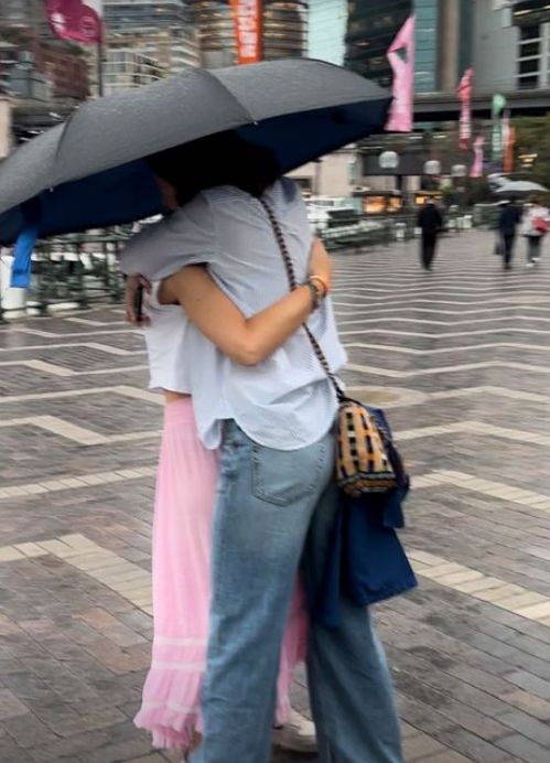 Jools Oliver and daughter Poppy hugging under an umbrella