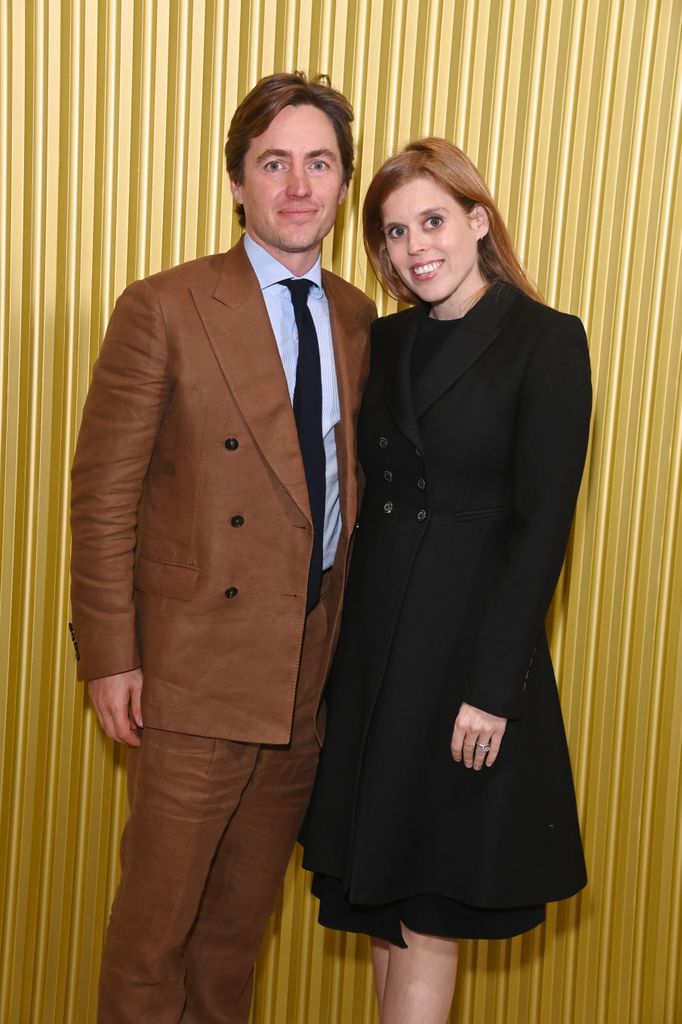 Princess Beatrice smiling in black dress with Edoardo in brown suit