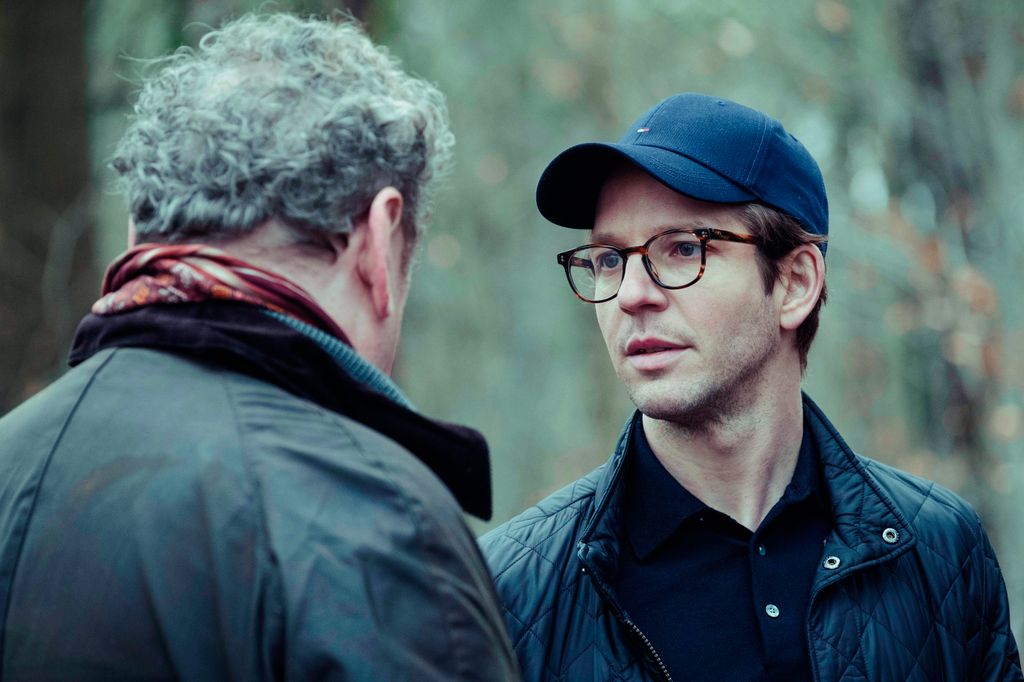 man in glasses and cap talking to older man