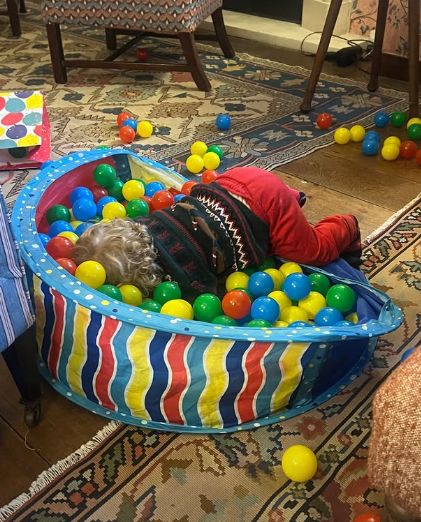 A young ball fallen over inside a ball pit