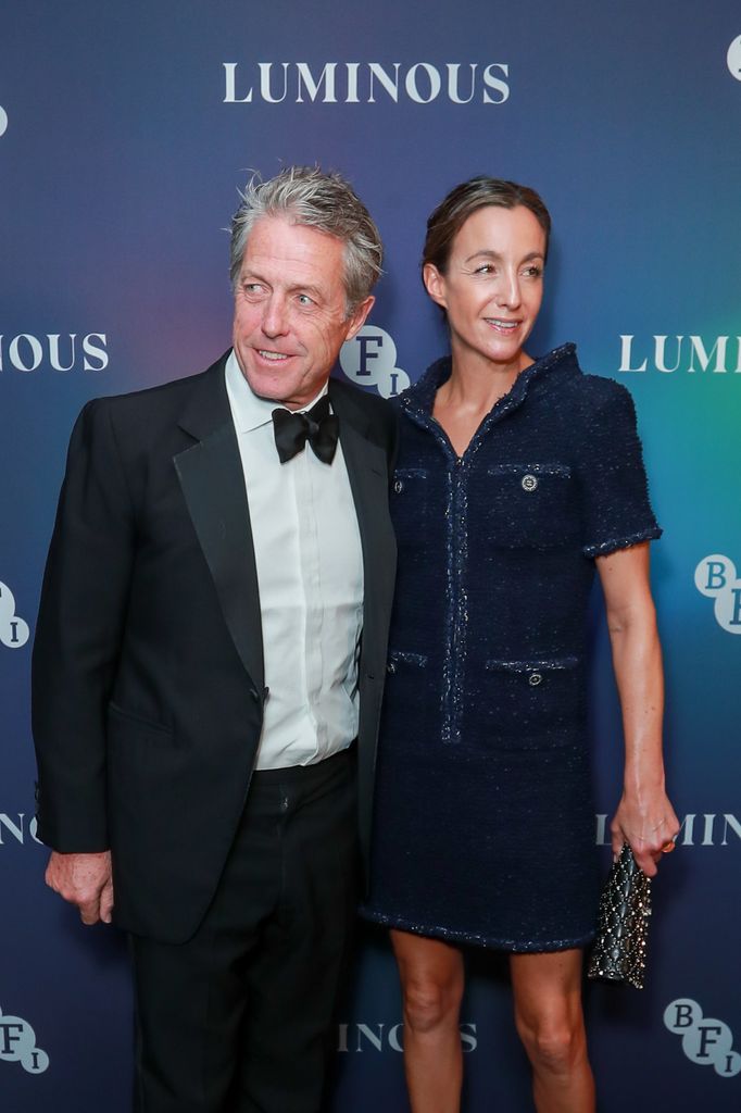 Hugh Grant in a black tuxedo and Anna Eberstein in a denim dress