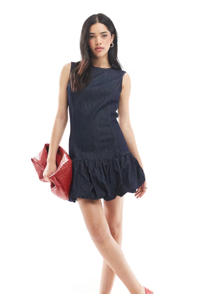 A model poses in a Denim Puffball Mini Dress from Asos for their website