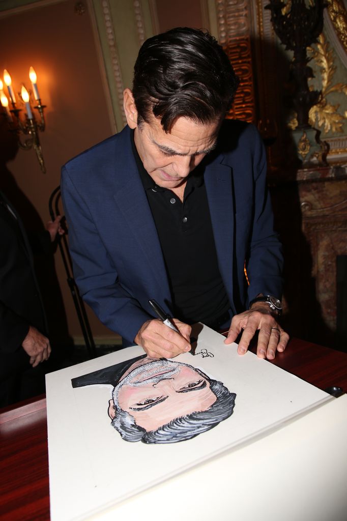 George Clooney signs his portrait during the unveiling ceremony for his Sardi's caricature in honor of his performance in "Good Night, and Good Luck" on Broadway at Sardi's 