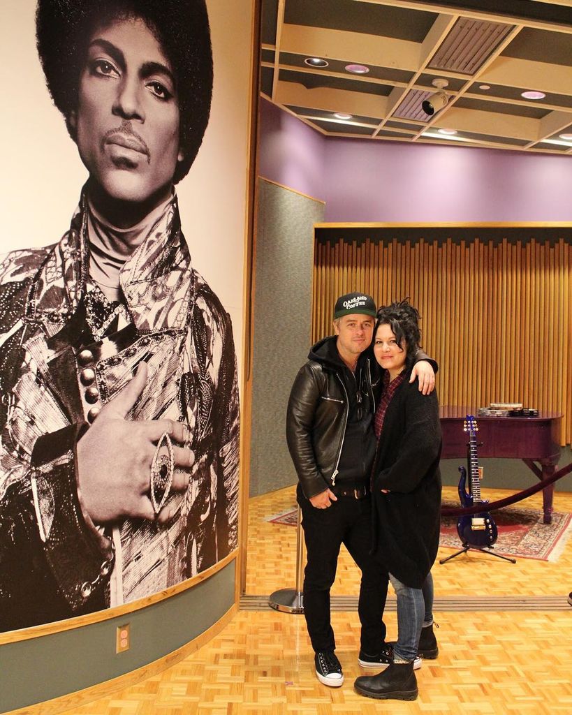 billie joe armstrong and wife adrienne standing in front of prince photo in recording room