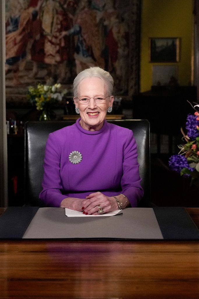 Queen Margrethe at table in purple dress with brooch