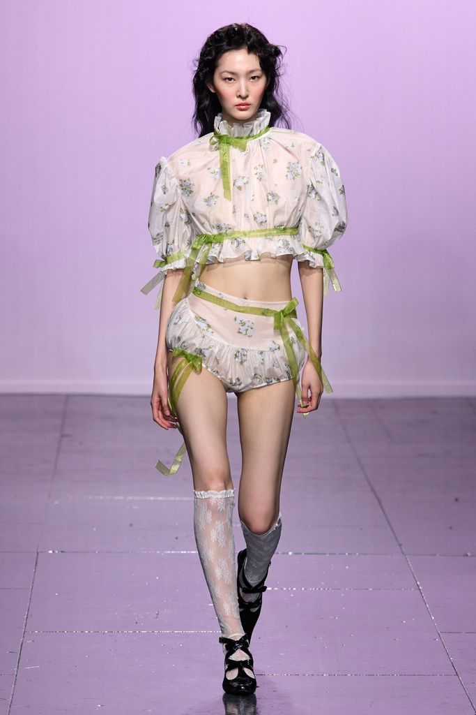 A model wears sheer lace bloomer shorts and matching crop top at Yuhan Wang SS24