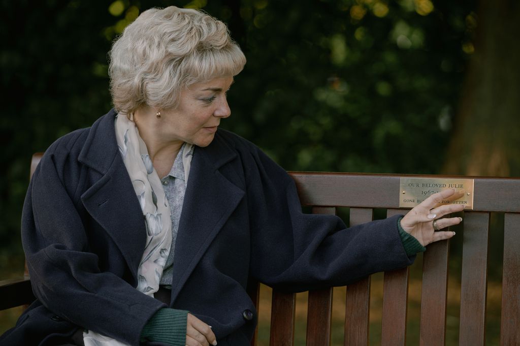 A woman touches a memorial bench