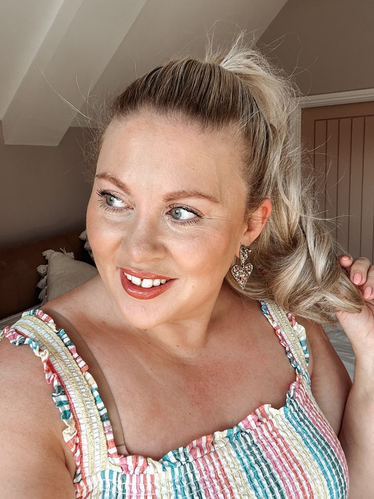 Woman with striped dress and ponytail smiling and looking off camera