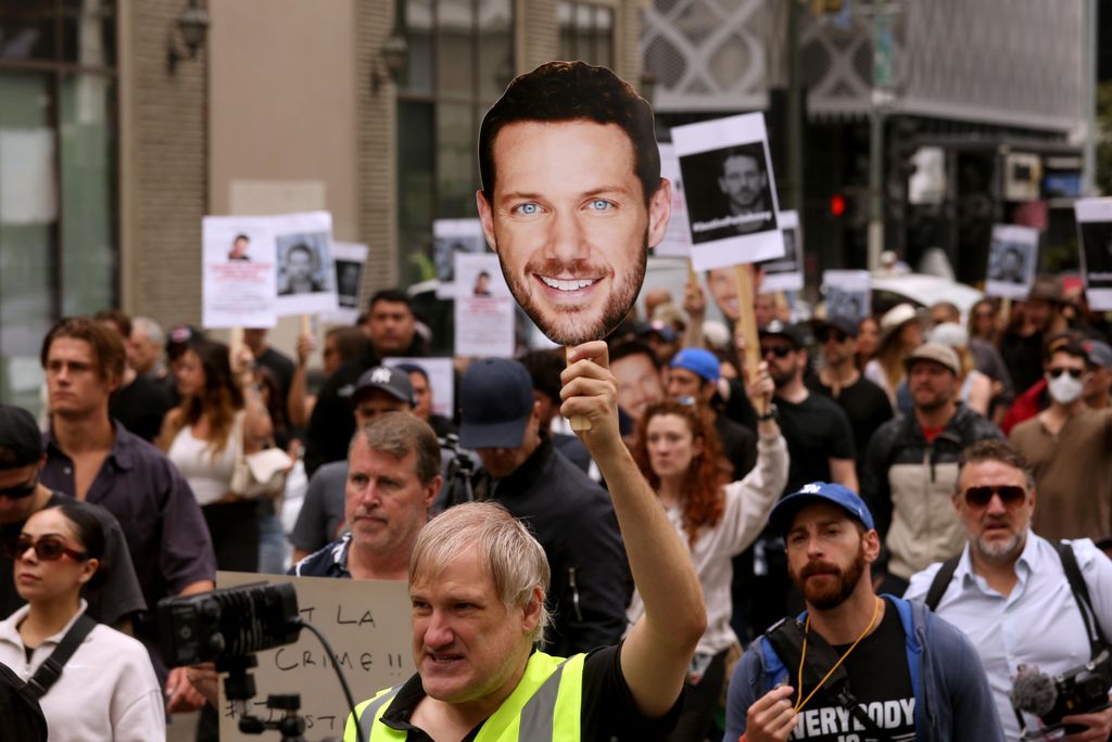 Actor Kevin Suscavage, holding a picture of actor Johnny Wactor, marches with more than a hundred friends, actors and family members who marched to City Hall to demand justice