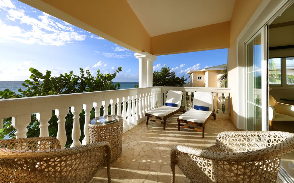 balcony with two sun loungers and chairs with sea in the distnace