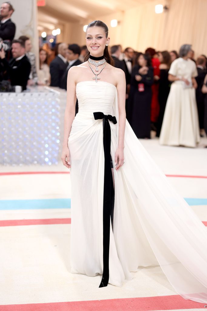 Nicola Peltz Beckham in a white gown and black sash at the met gala