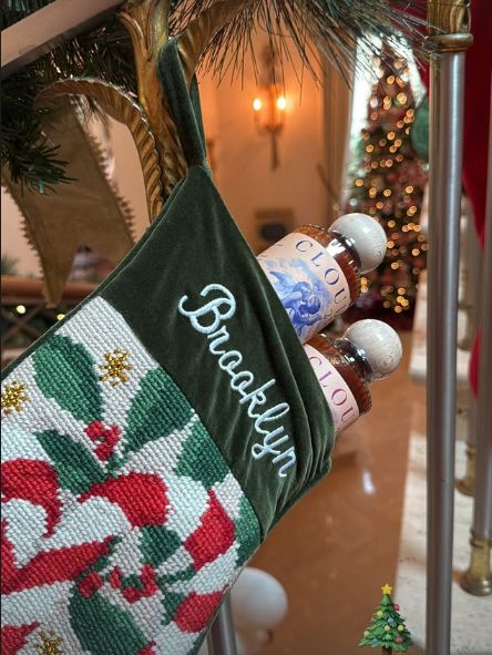 A stocking hanging on a branch with a Christmas tree in the background