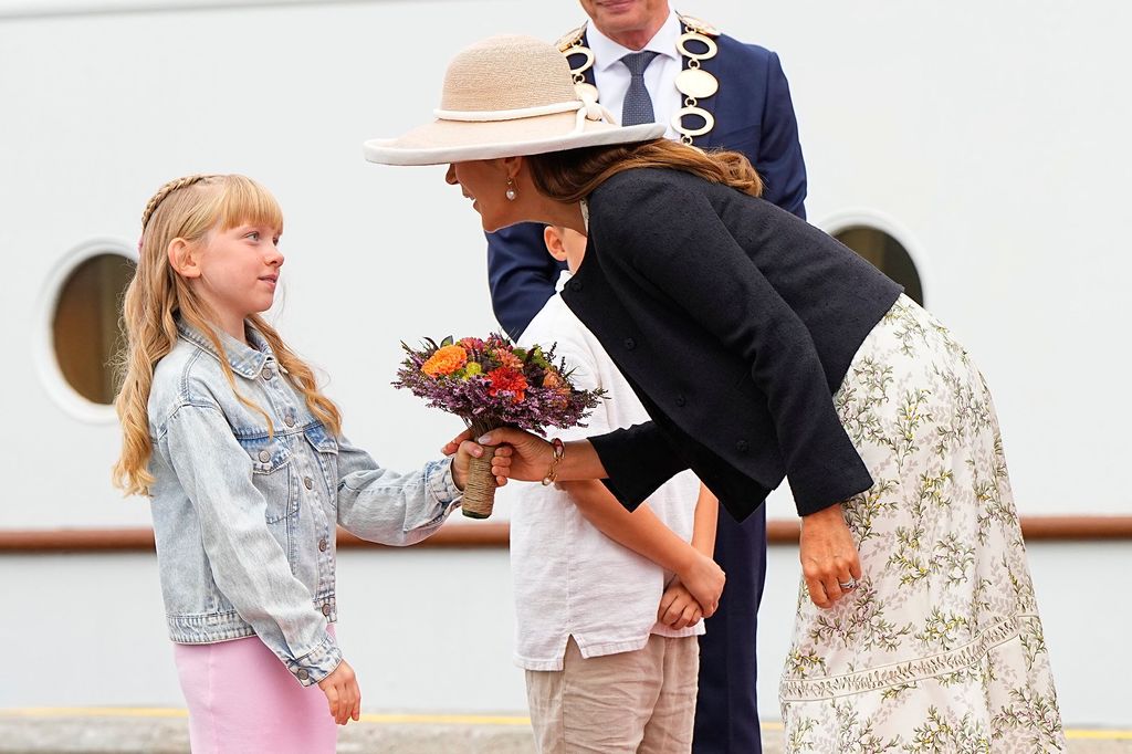 Queen Mary with King Frederik, Mary is receiving a bunch of flowers from a young girl