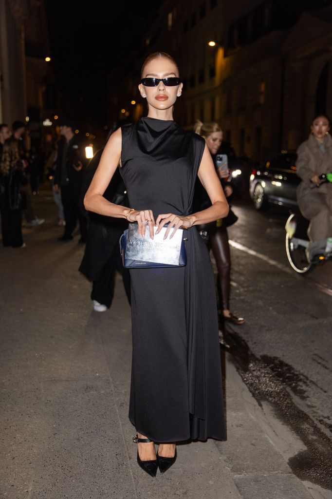 Jordanna Maia wears black tailored sleeveless dress, bag, sunglasses outside Victoria Beckham during the Womenswear Fall/Winter 2025/2026