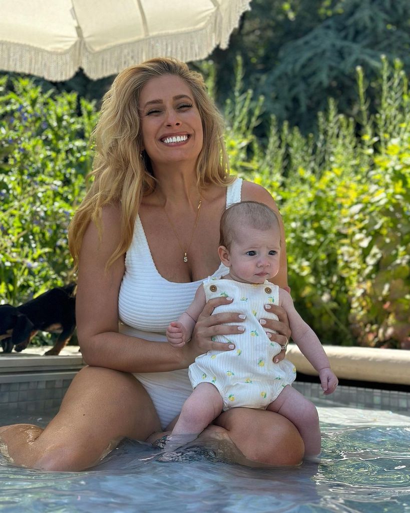 Stacey Solomon posing in a white to-piece whilst holding her daughter Belle