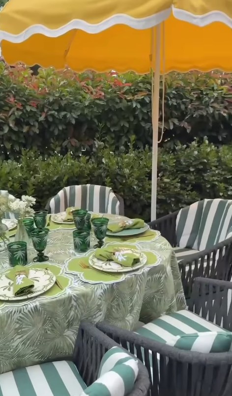 Dining table laid with green botanical theme and yellow parasol covering above