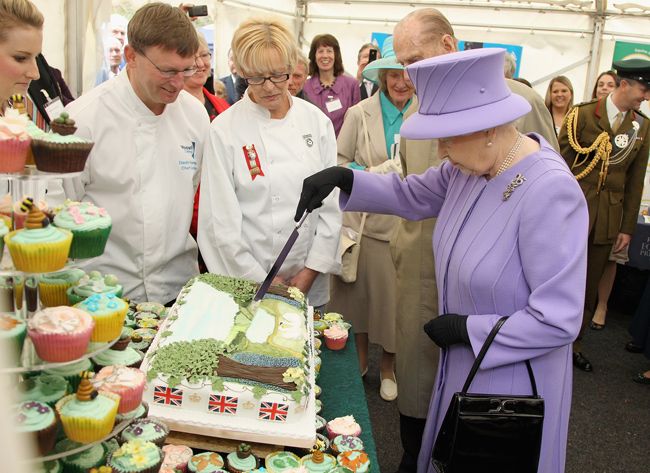 the queen cuts a cake 