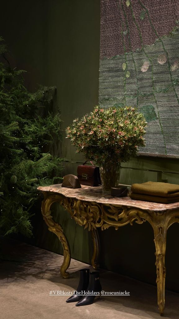 A console table with a bouquet of flowers with a christmas tree in the background