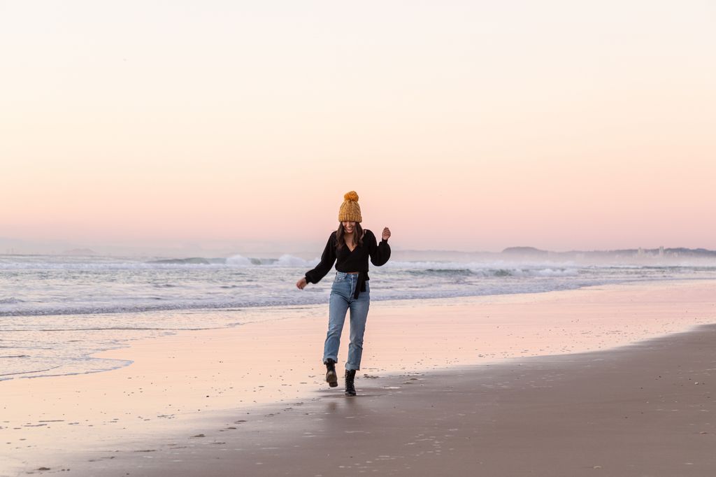 Young Asian lady dressed for winter walking on the beach at sunrise on the Gold coast