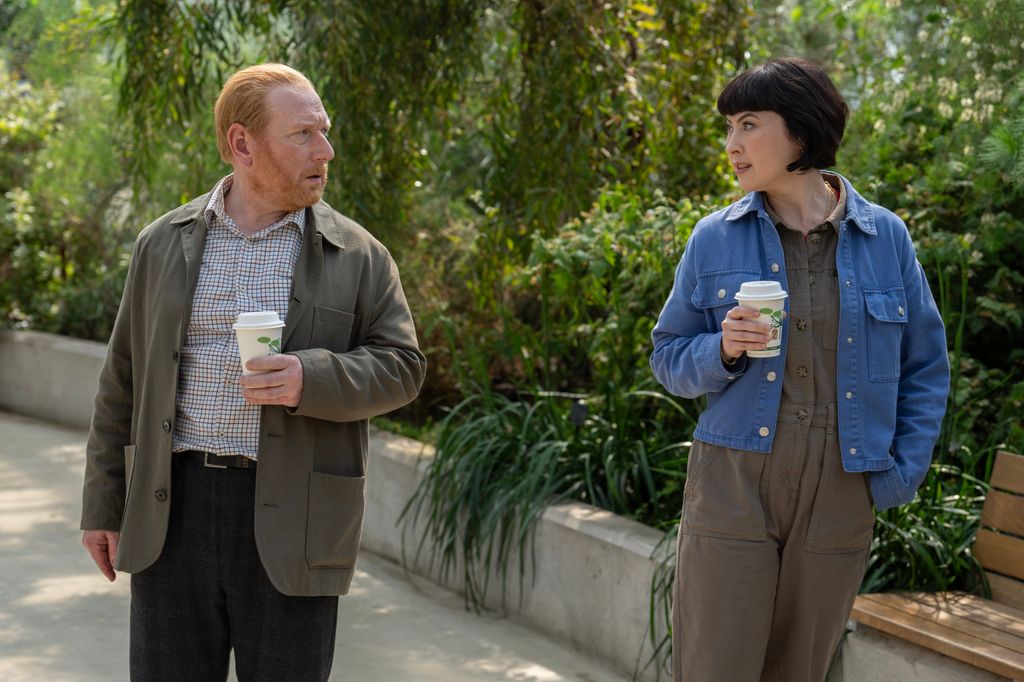 man and woman walking and holding coffee cups