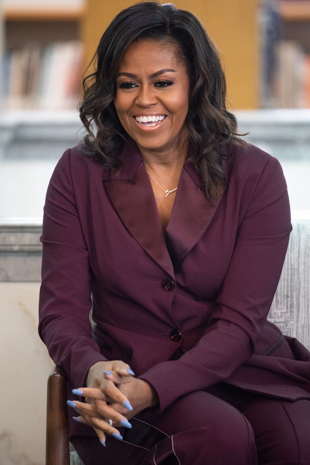 Michelle Obama in a maroon suit smiling with her hair in curls