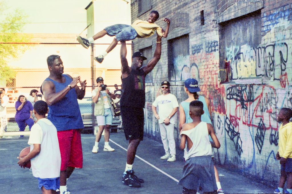 Shaquille O'Neal carries a little boy over his head on the set of the Pepsi "Shaq Playground" commercial in 1994
