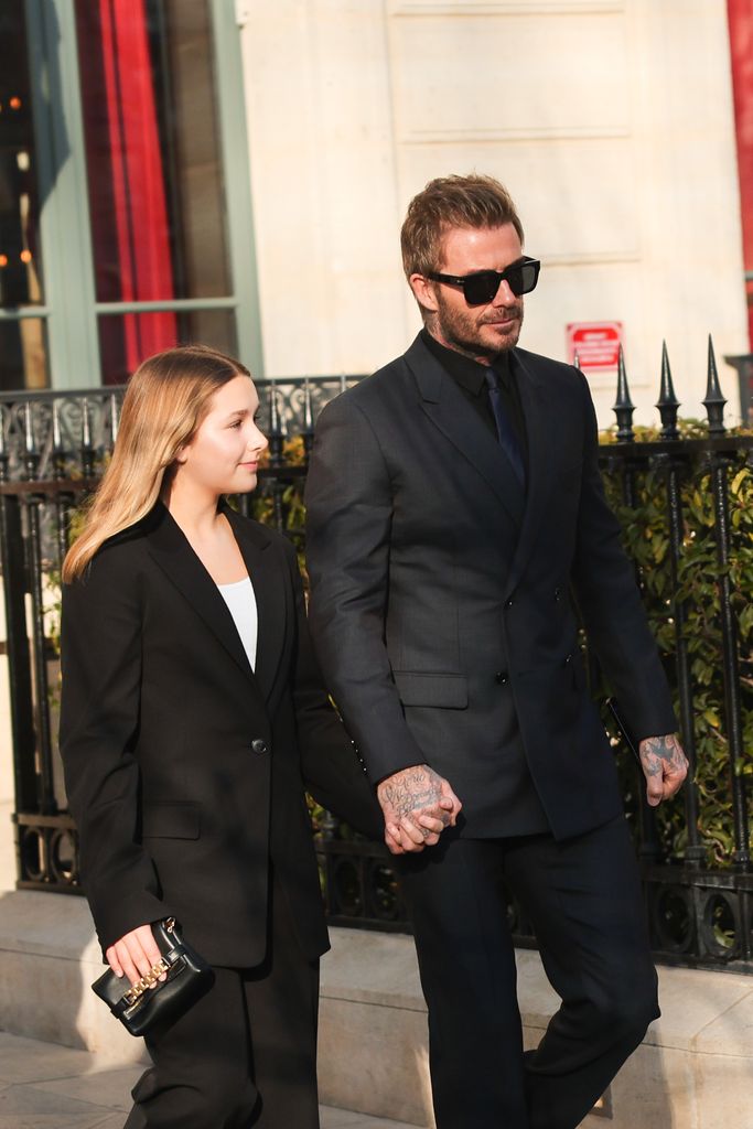 David and Harper Beckham walking along in black clothes