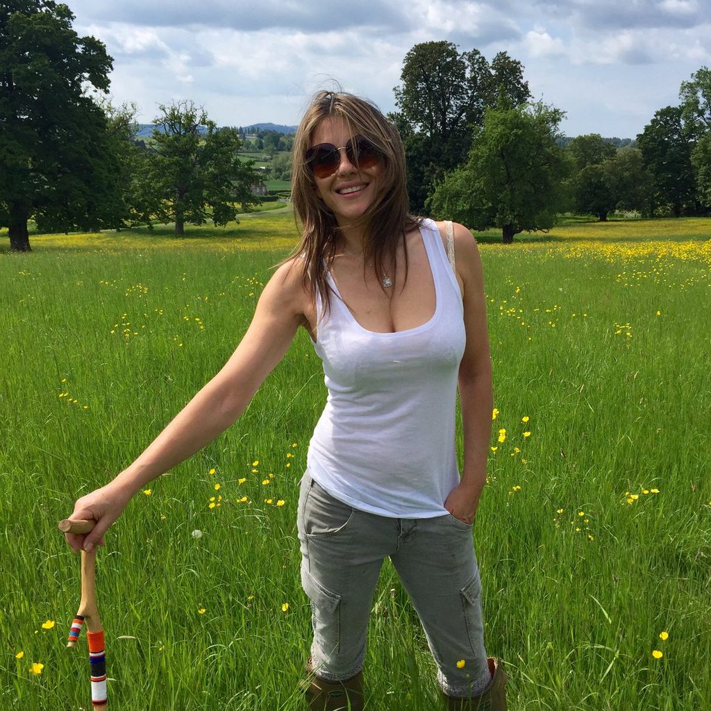 Elizabeth Hurley in skinny jeans and white vest top posing in Cotswolds field