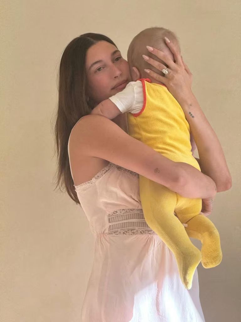 Hailey bieber holding baby Jack Blues in yellow onesie